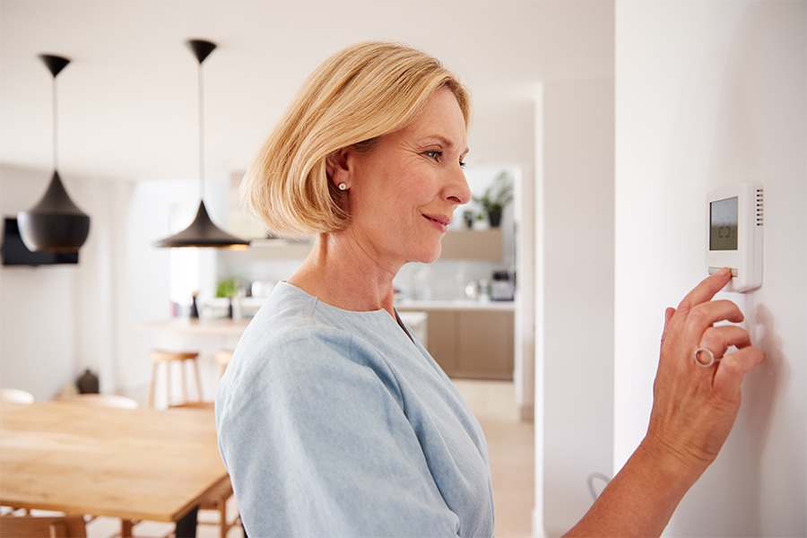 woman adjusting the thermostat